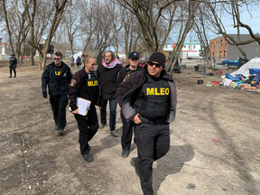 City of Kingston Bylaw Enforcement officers at the Belle Park encampment enforcing the day time ban on camping as Ivan Stoiljkovic (wearing red and white scarf) of the Katarokwi Union of Tenants, loudly criticizes their actions in Kingston, Ont., on Tuesday, April 2, 2024. (Elliot Ferguson/The Whig-Standard/Postmedia Network)